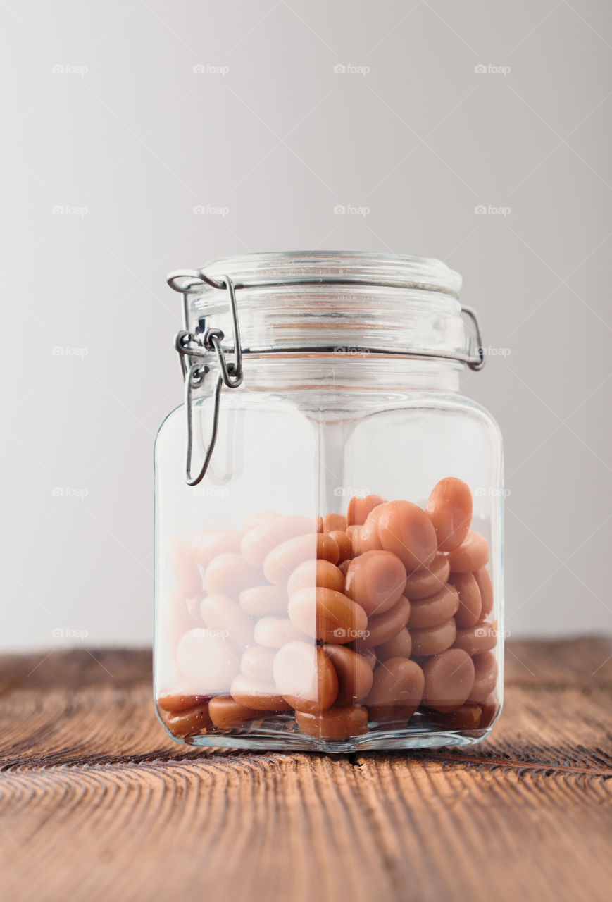 Jar filled with caramel milky candies on wooden table