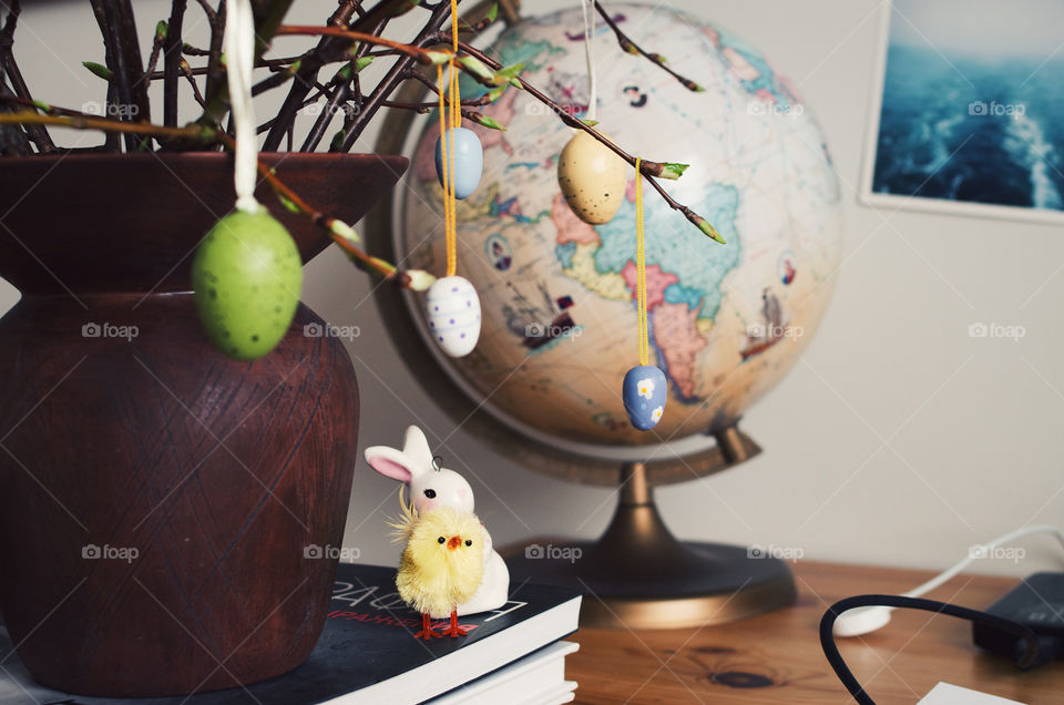 Colourful tiny Easter eggs hanging from the ament branches with a little chick and a bunny in the background.