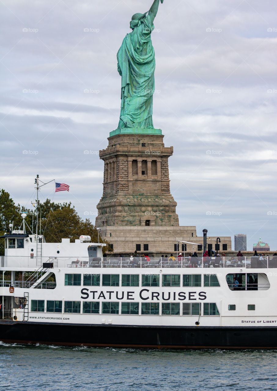 An American flag seen in the background as a Statue Cruises ferry your boat passes the Statue of Liberty. 