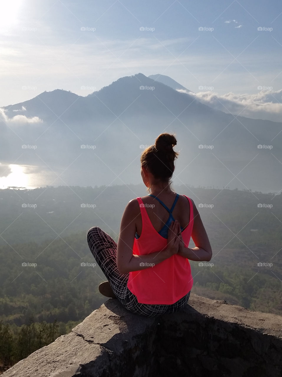 Young millennial woman meditate at the top of the mountain