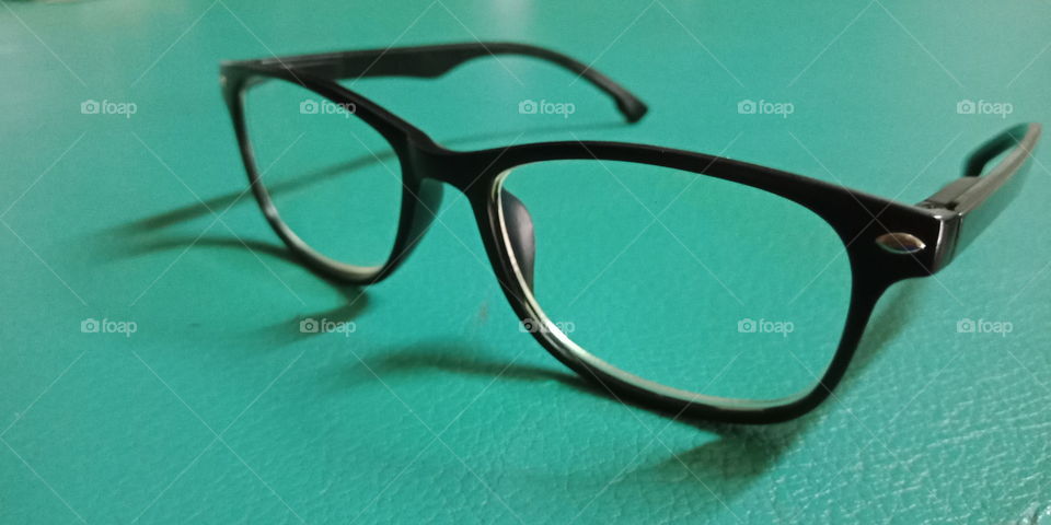 The black plastic eyeglasses on green surface