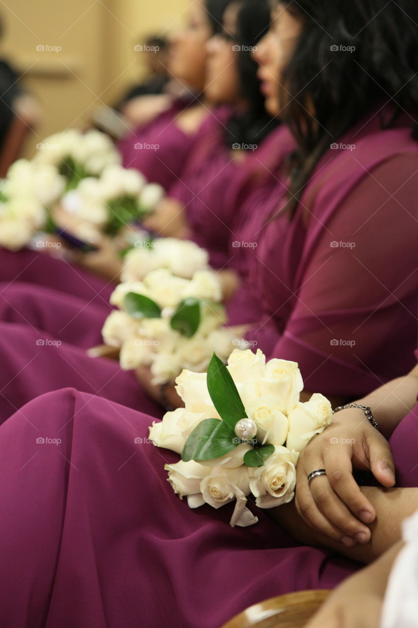 Bridesmaids sit in a row as they listen closely at a wedding ceremony.