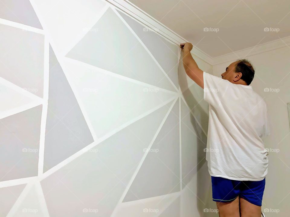 Man painting the wall in the shape of a triangle