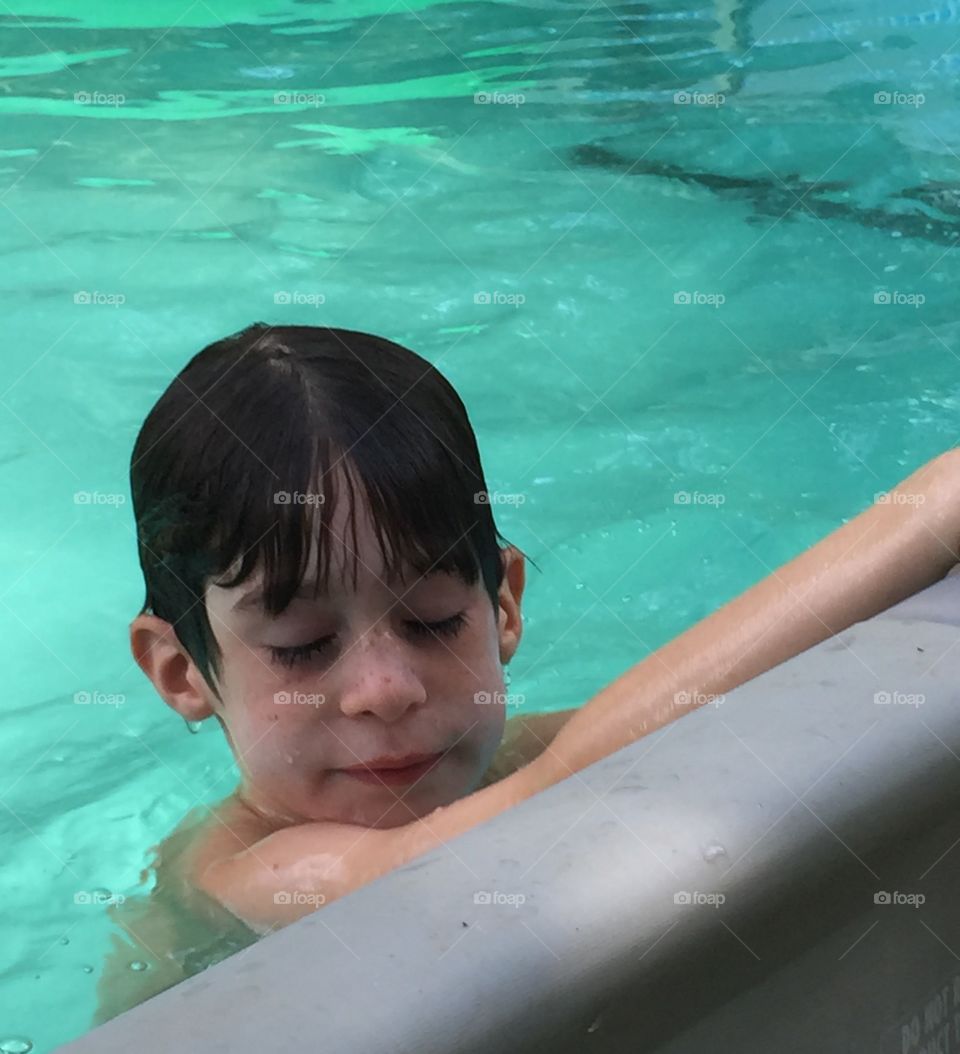Six year old boy in the pool in summer.