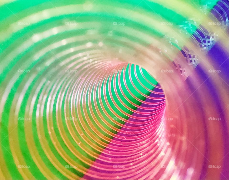 Pinky green, vibrant abstract photo created by shooting through a slinky against coloured card