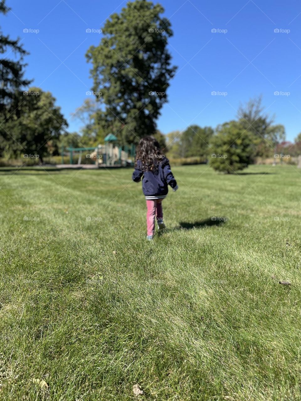 Little girl running towards park, toddler running in the park, little girl excited about playground equipment, playing in the park in the fall 