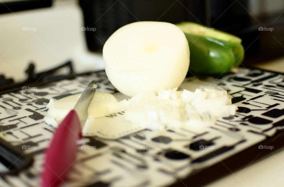 Fresh onions and bell peppers on cutting board with a knife 