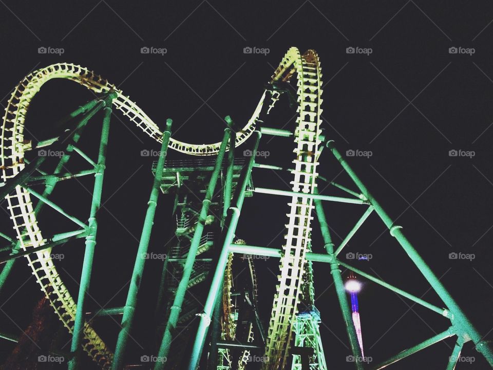 Taking a ride on a thrilling green roller coaster in the pitch black but lit with lights. 