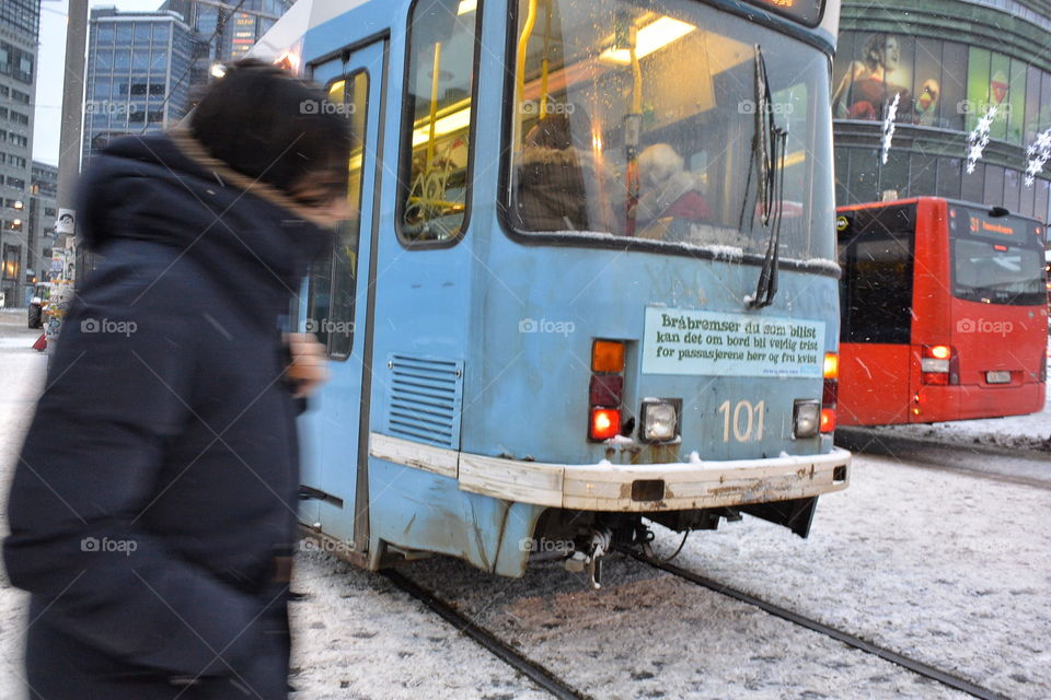 Tram and bus passing commuter in snow