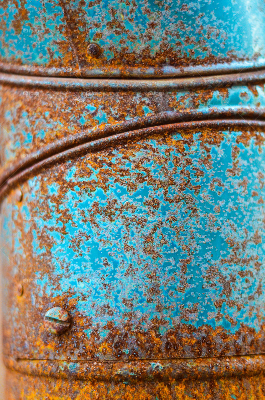 dark reds and oranges of rust slowly, inexorably, inevitably creeps across the turquoise surface of a chimney creating a stark contrast of beautiful colors