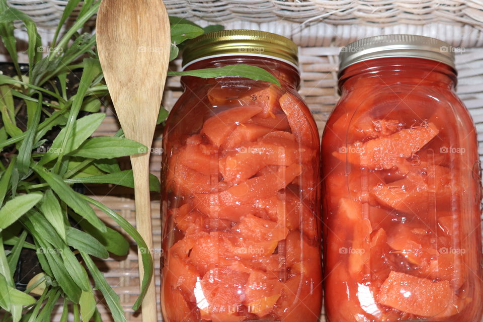 Flat lay two jars of quince fruit preserves in wicker basket 