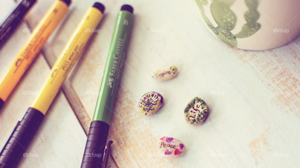 Creativity, life, inspire, peace conceptual art on tiny stones on vintage wood table with PITT Artist pens by Faber-Castell and coffee mug - abstract tranquility and leading a creative life in Little everyday things photography 