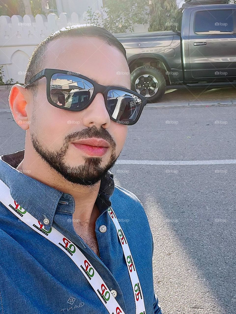 A selfie of a man during a workday on a street with a pickup truck in the background.
