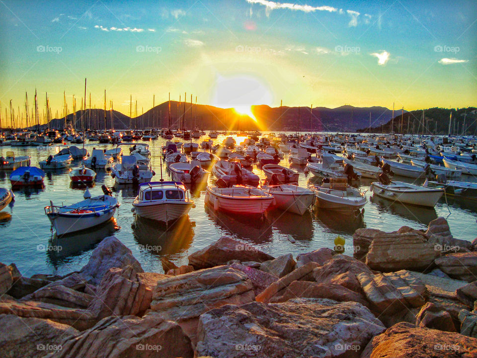private yacht and boats parked at the Lerici coast in Italy and sunflares falling on them during sunset or golden hours