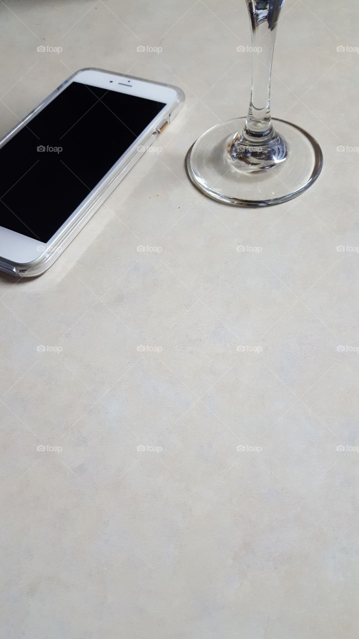 white tabletop with phone and wine glass