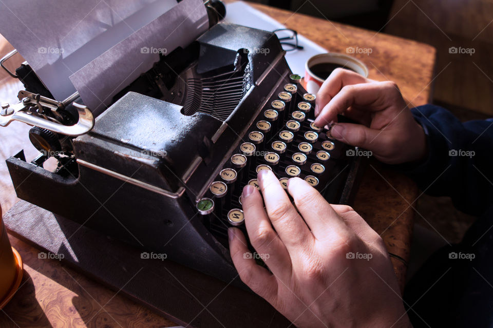 A young writer is writing a new book on an old typewriter.