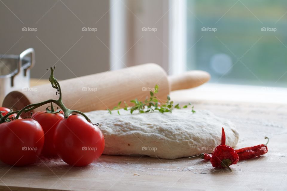 Rolling pin with tomato and spice on wooden board