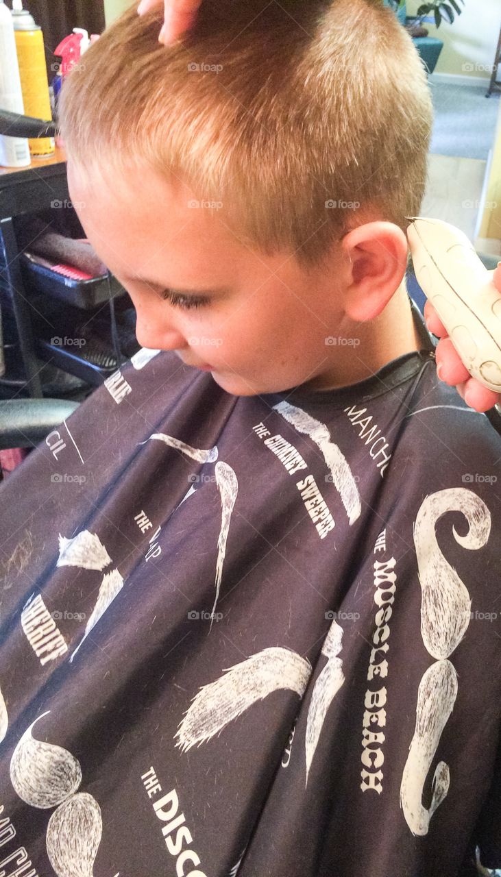 Hairdresser's hands making hairstyle to boy