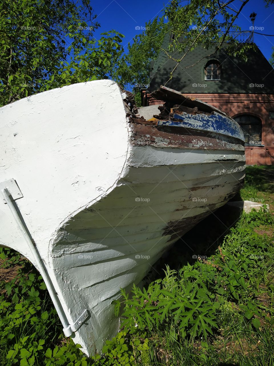 Old broken wooden boat that lies on green grass