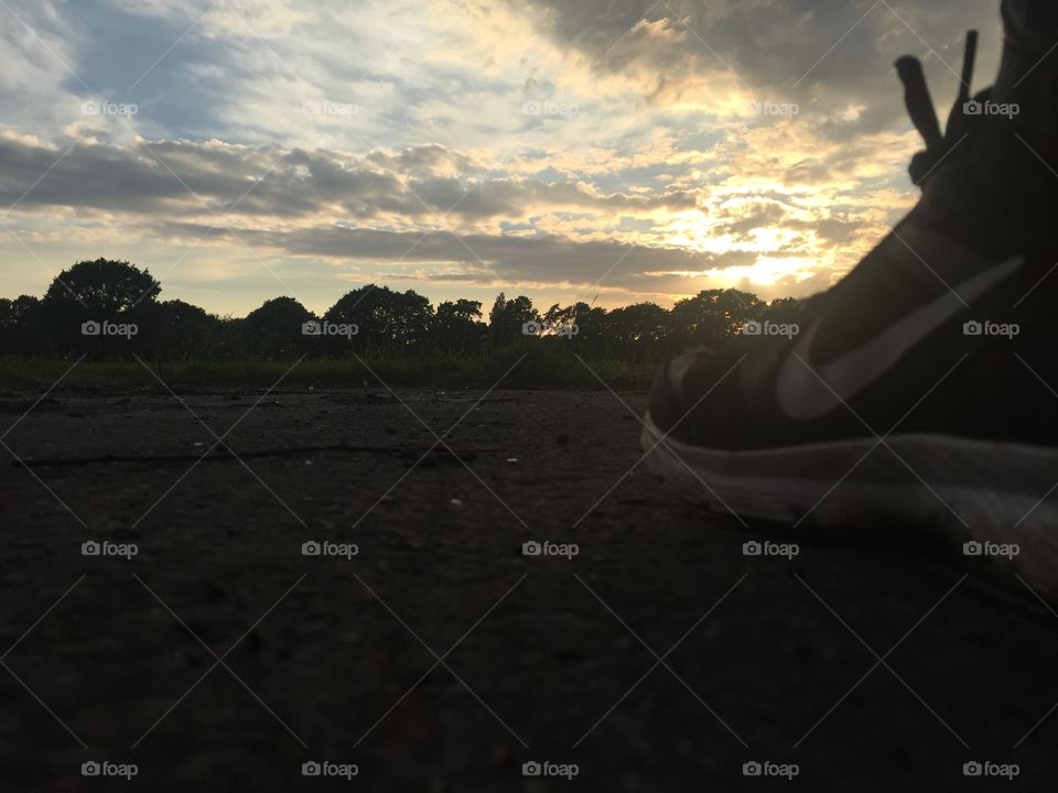 Floor view of Nike shoes looking forward towards trees and a nice sunset