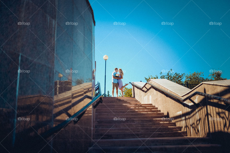 парень с девушкой стоя обнимаются на лестнице