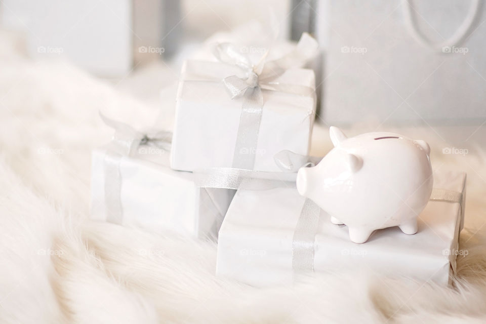 piggy bank with 100 dollars banknote in festive New Year atmosphere of scenery.  Magical bokeh with Christmas tree and bright lights.