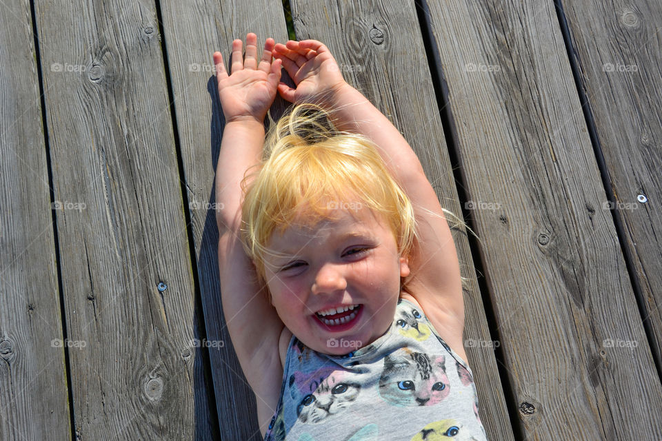 Little girl playing and loughing while she is on the ground.