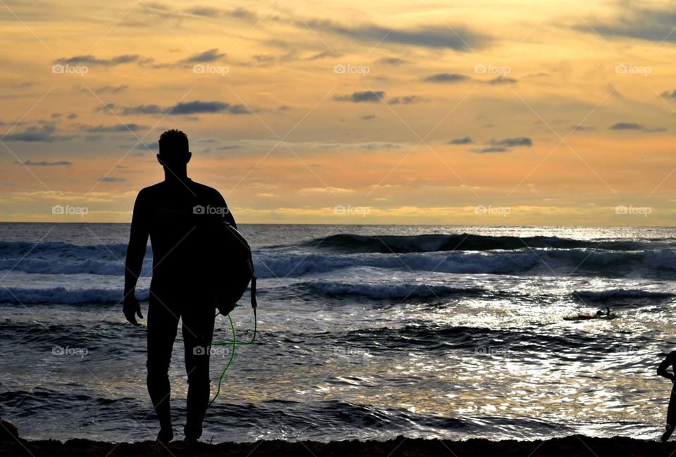 Silhouette of surfer with sea in background.