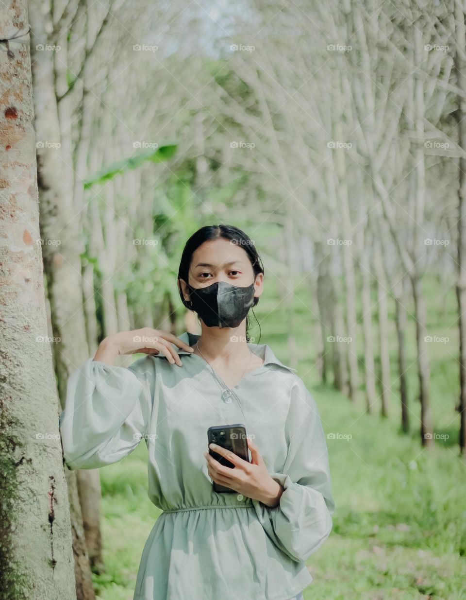 masked girl holding smartphone in nature