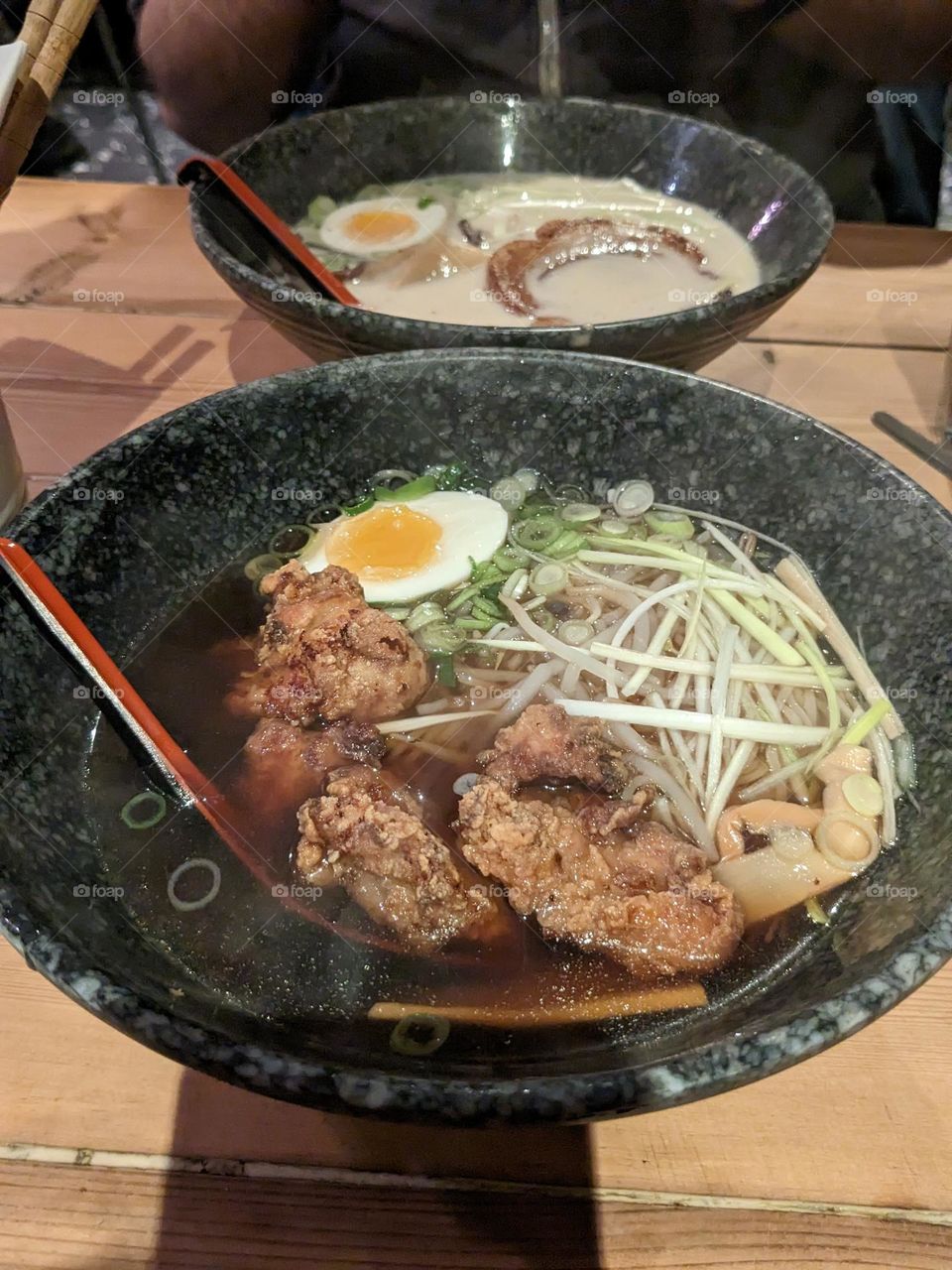 date night ramen large bowls of ramen. one has a creamy base and pork, the other has a darker broth and pieces of fried chicken