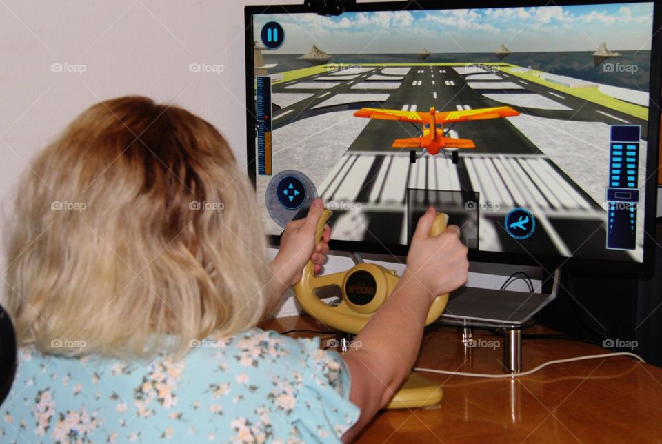 Woman using flight yoke landing plane in video flight simulator 