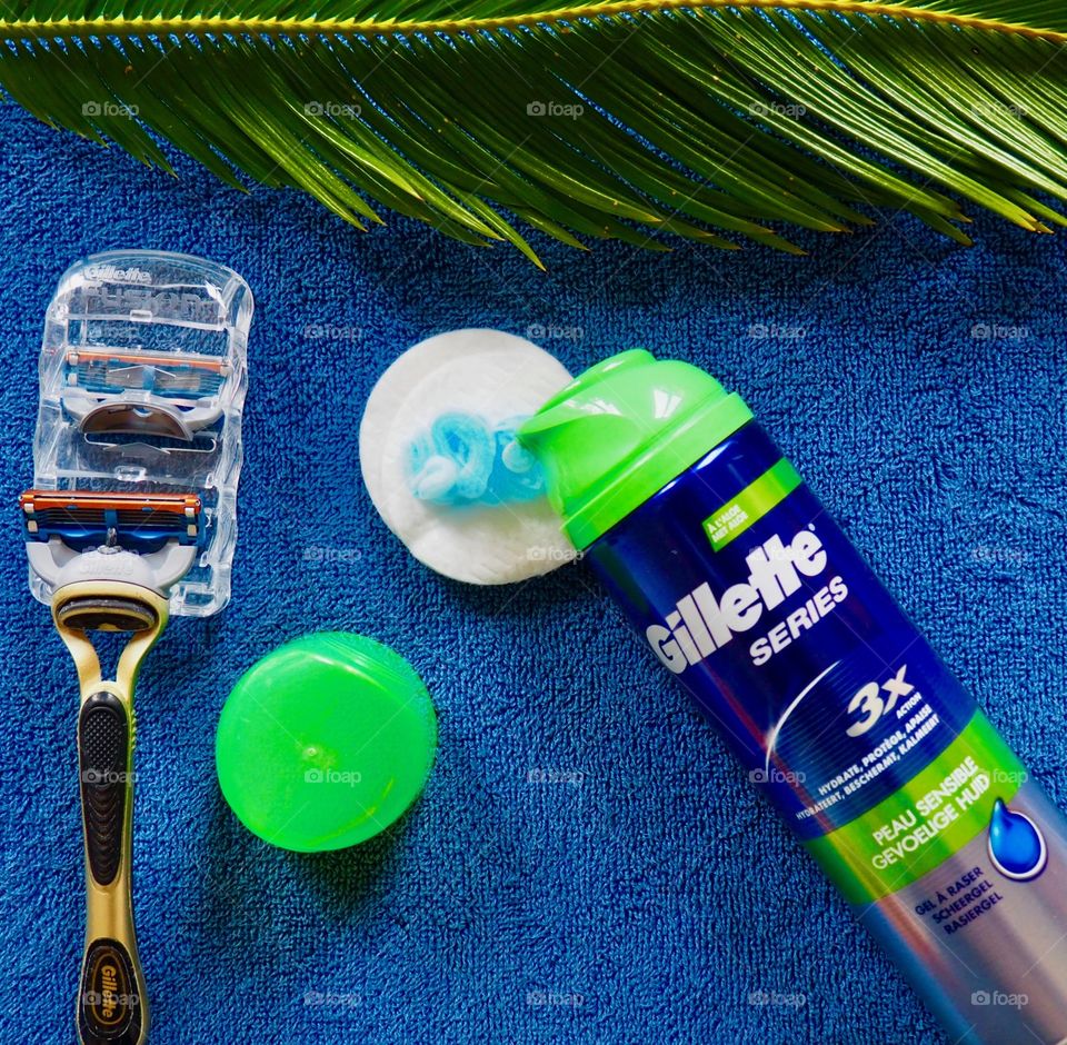 Gillette shaving cream and razor on a blue towel.