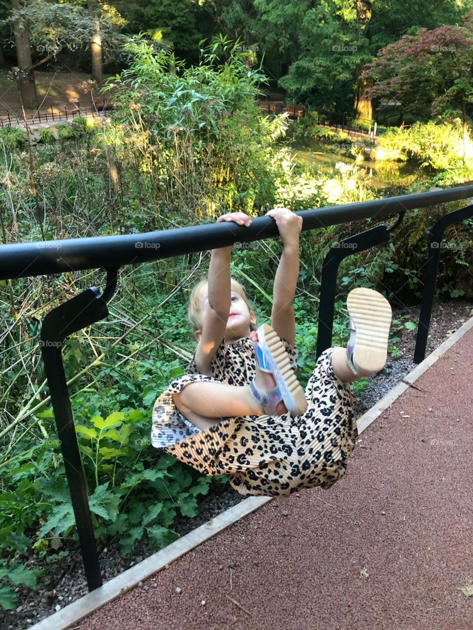 Little girl swinging on the rails at the park 