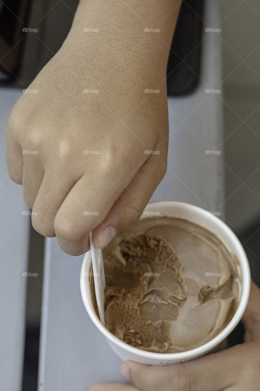 Hand boy holding the spoon Ice cream scoop in a cup.