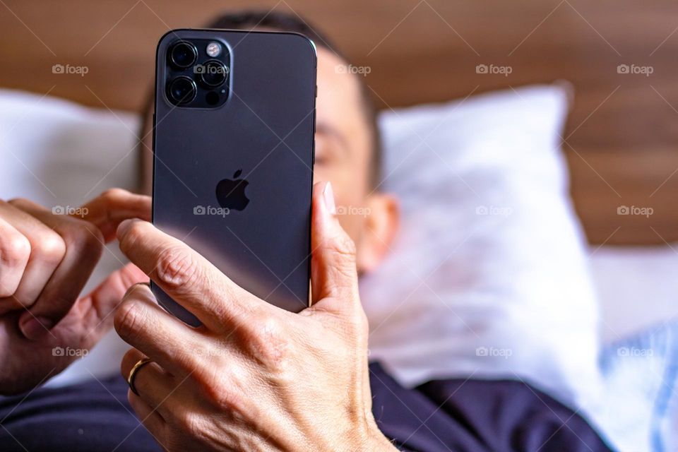 Man relaxing in bed using cellphone