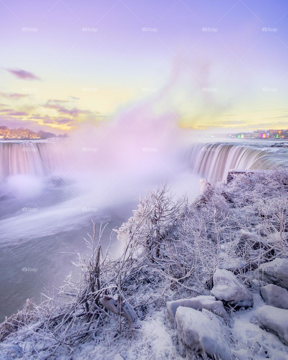 Beautiful serene winter wonderland as snow covers the landscape with a waterfall in the background - Niagara Falls 