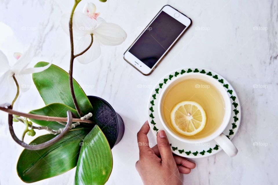 Close-up of a person's hand holding cup of lemon tea