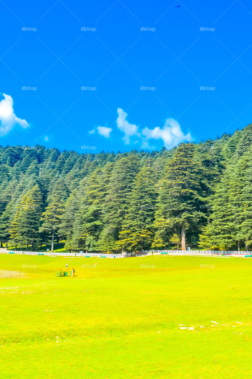 A beautiful golf course on a hill station with road blue sky trees clouds. Captured in sunny day hill station India taken landscape style useful for background wallpaper screen saver Vacation Concept
