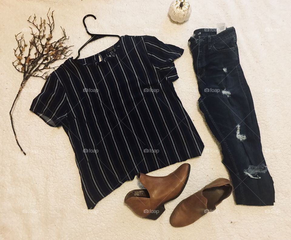 Fashion for the fall season : women and teen girls fashion : brown boots , striped blue and white dress shirt and dark wash denim torn jeans.