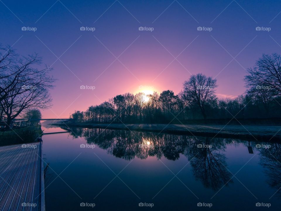 Countryside sunrise showing the colorful sky reflected in the water of the river 