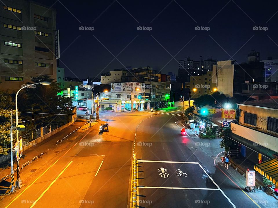 An empty intersection at nighttime in Changhua, Taiwan. There are buildings in the distance, and to both sides. 