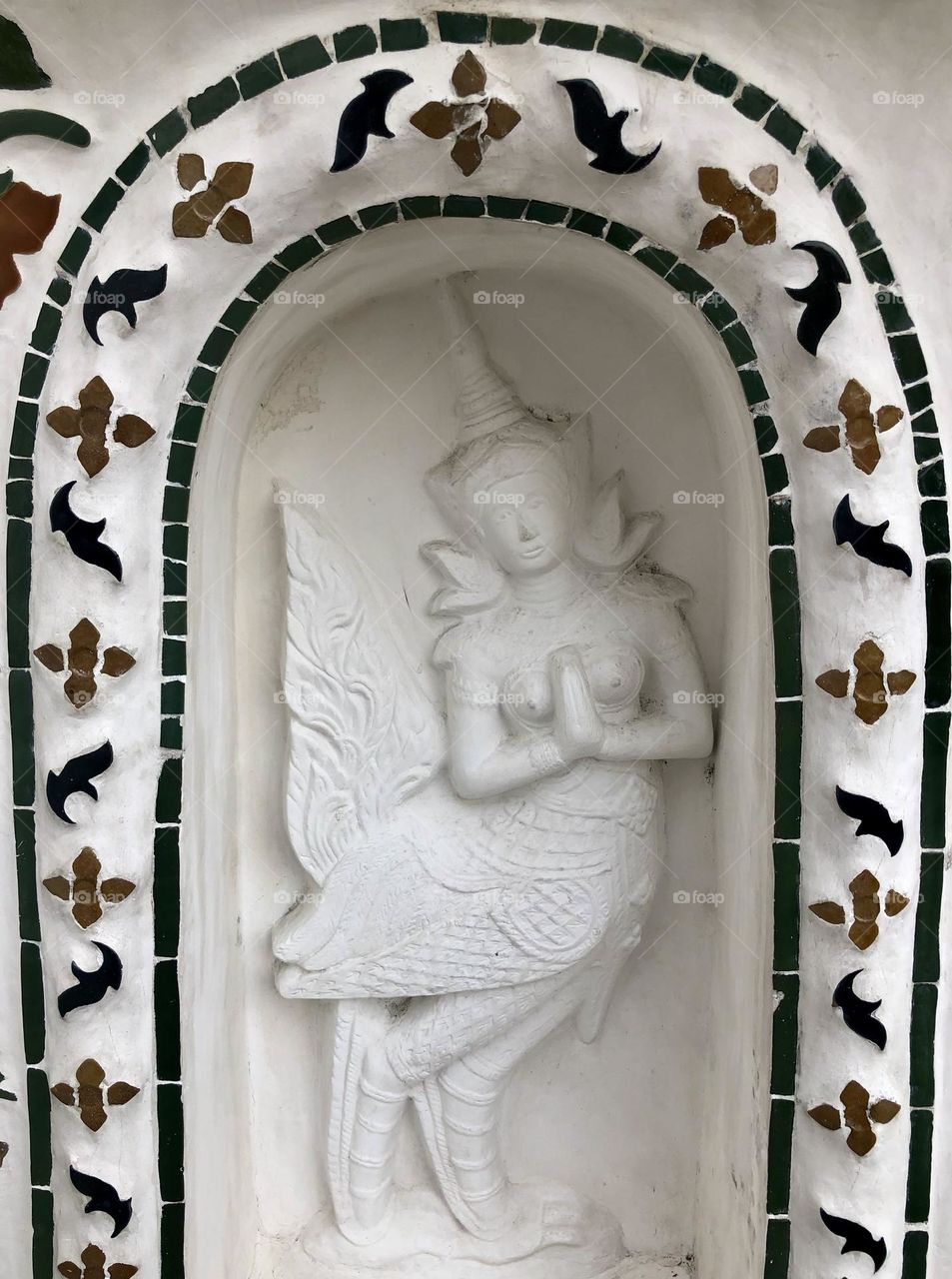 White painted Indonesian mythological figure statue framed by decorative arch