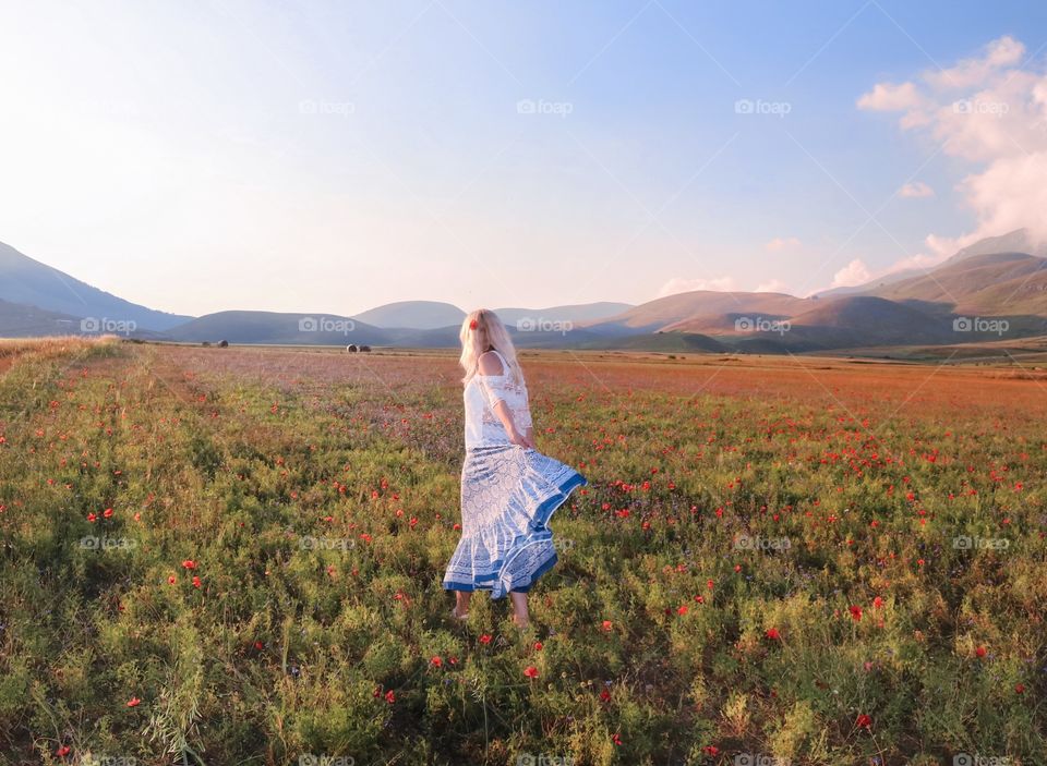 blonde runs on a flowering poppy field