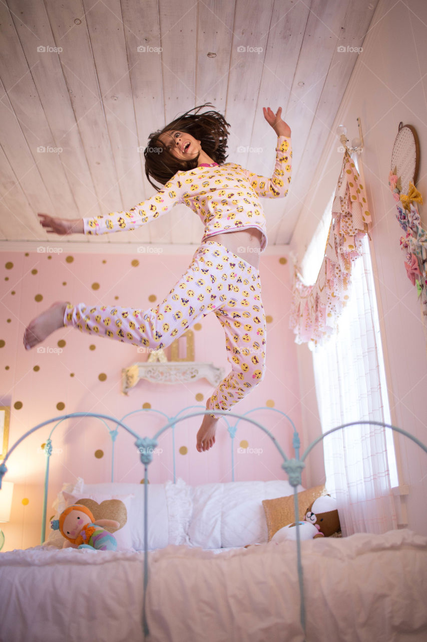 Girl jumping on on the bed in pajamas