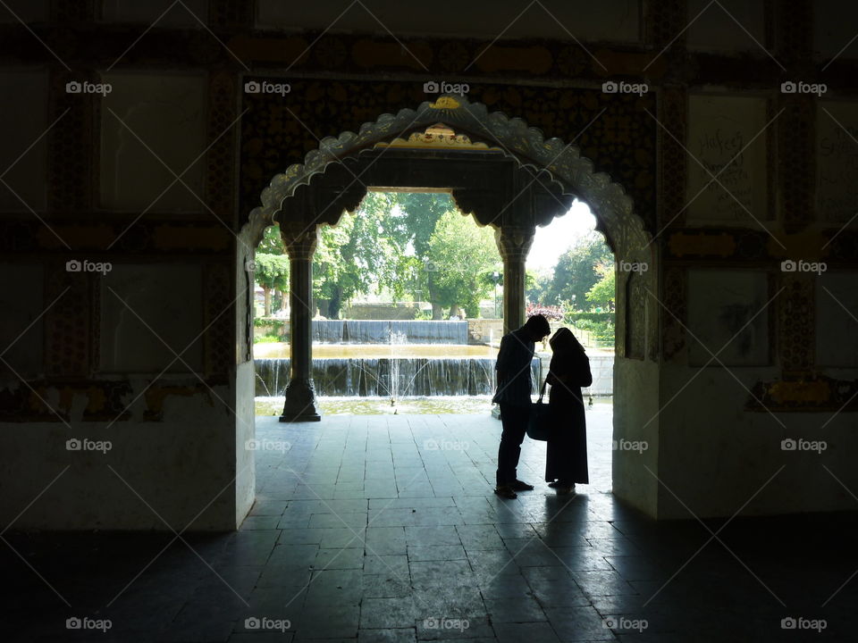 two silhouette people under a oriental porch and near to fountains