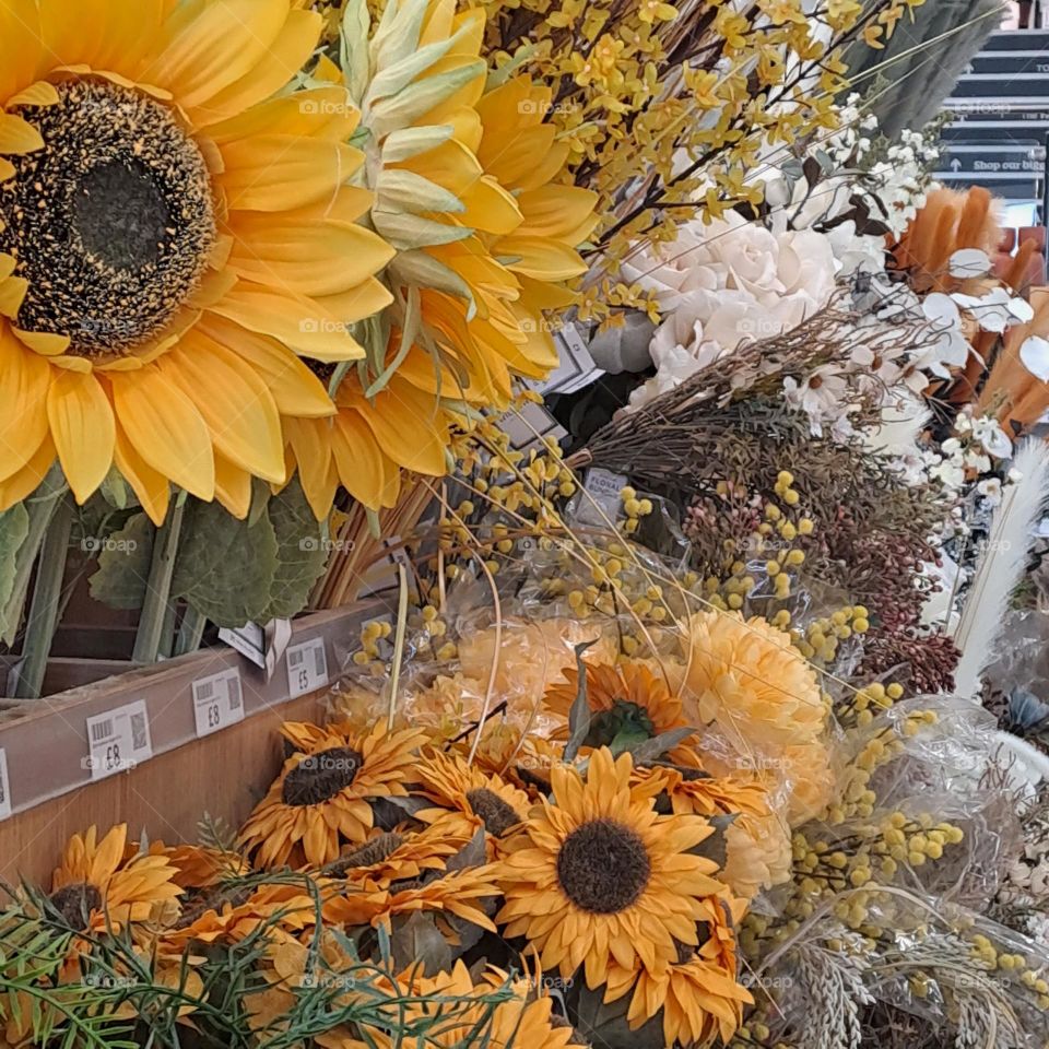bright artificial floral display in shop to buy. sunflowers, bright colours, autumn
