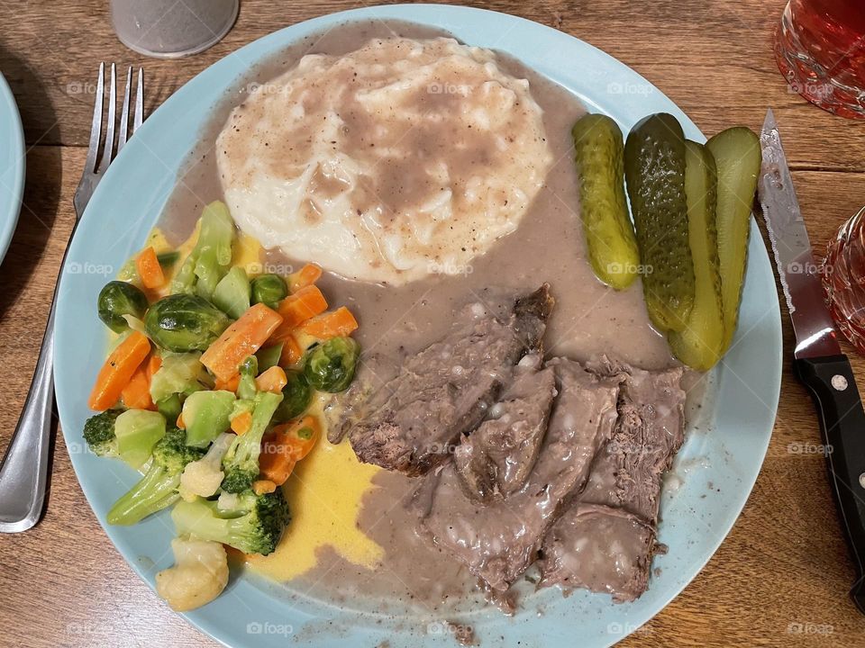 This teal plate of food was taken with my iPhone 12, on a special family occasion, consists of slow cooked beef roast, mashed potatoes, with lots of tasty beef gravy, pickles, and cheesy mixed veggies, was very delicious and filling