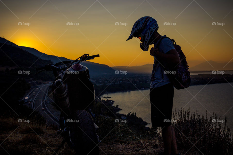 biker stops with his motorcycle after a roadtrip to gaze the sunset