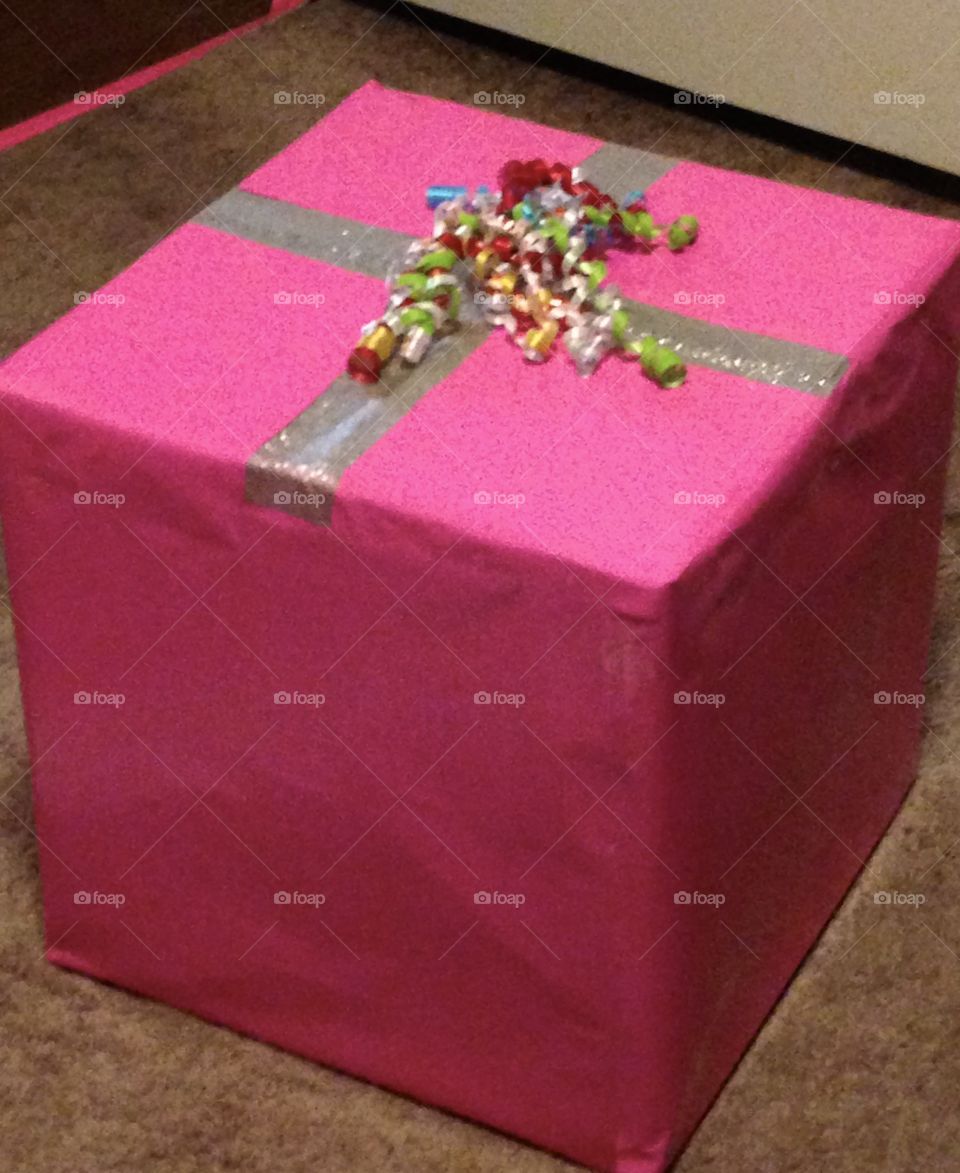 Large pink gift box with curly ribbon and glittery tape on top