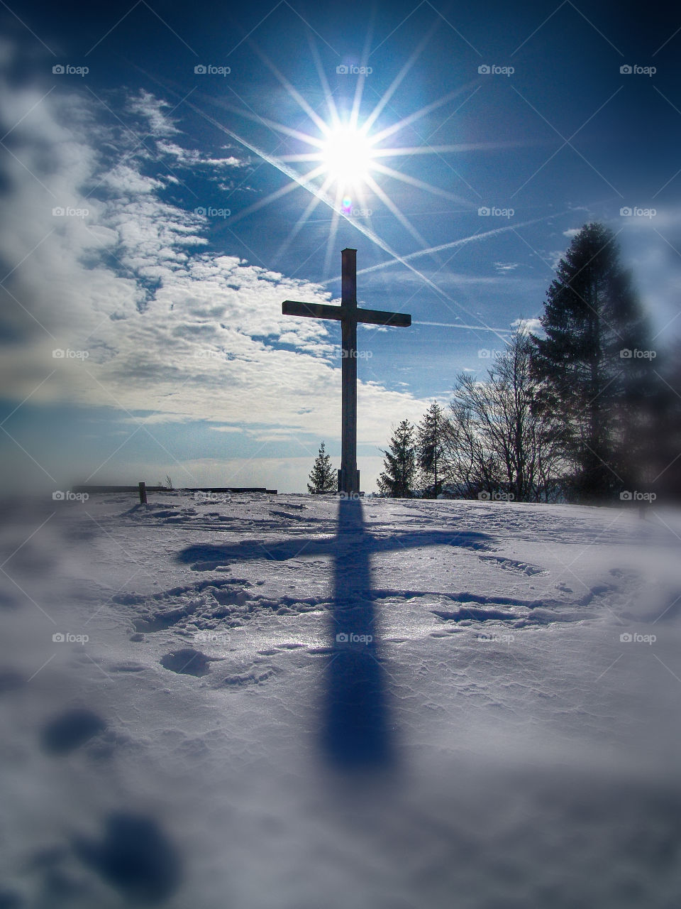 sun over the top of mountain with wooden cross